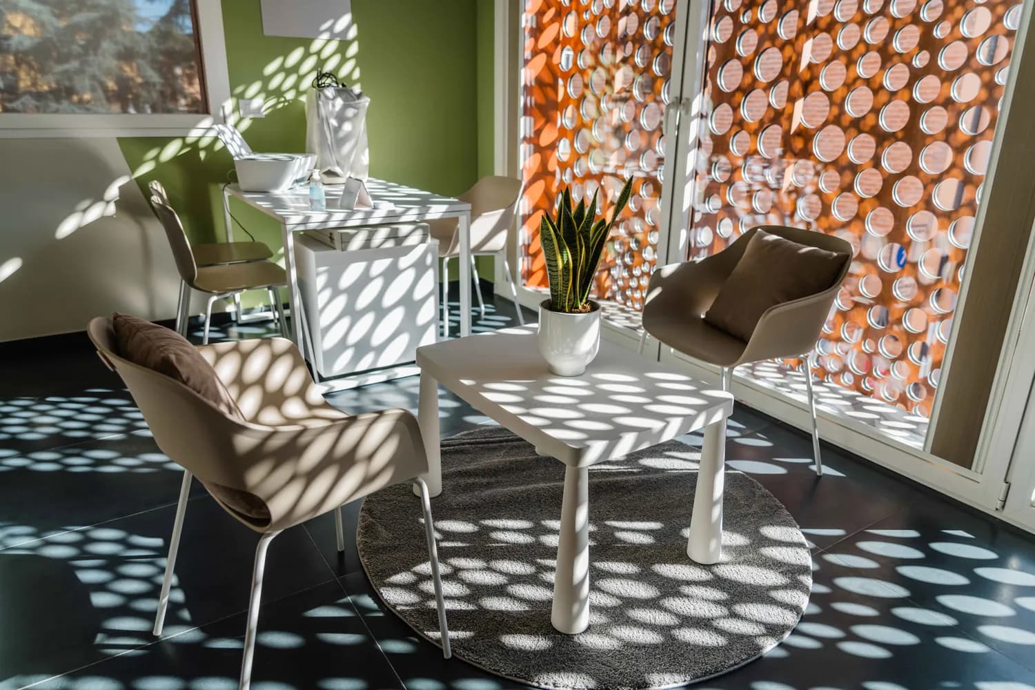 La sala d’attesa del Torresotto: tavolino, poltroncine e la luce che entra dalla schermatura traforata